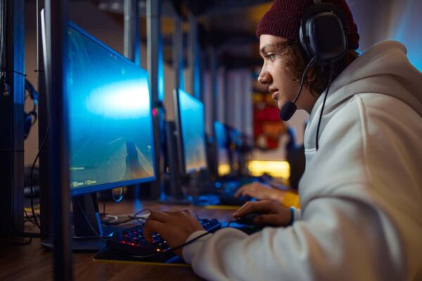 Jonge gamer geconcentreerd op een esports-wedstrijd, zittend voor een blauw verlicht scherm met headset en professionele gaminguitrusting.