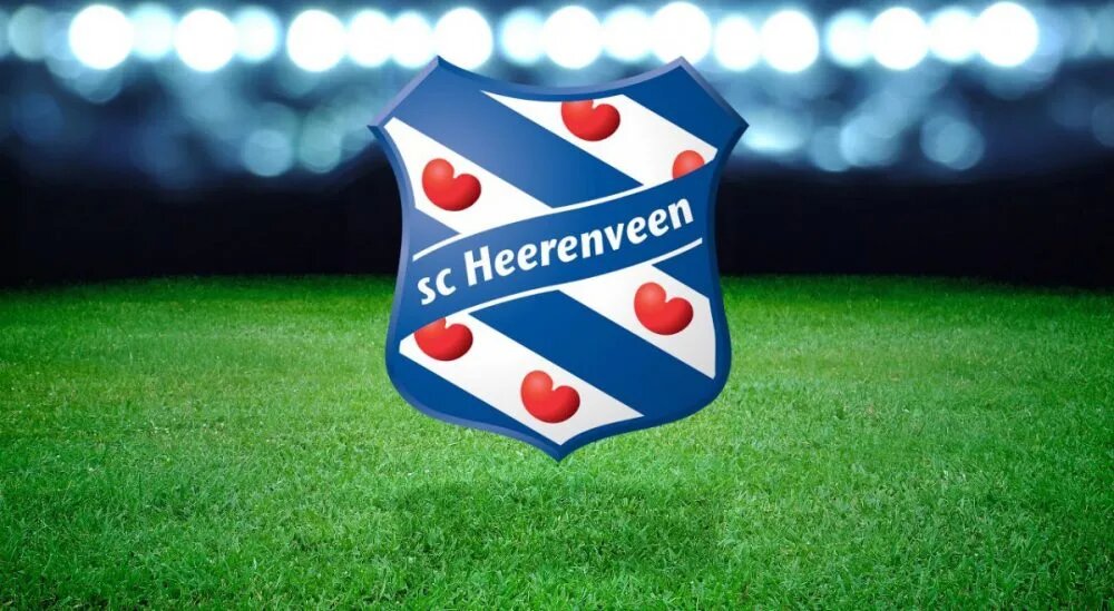 Het beeld toont het logo van sc Heerenveen, met een schildontwerp dat diagonaal blauwe en witte strepen bevat, samen met rode hartvormige symbolen die verwijzen naar het Friese erfgoed.