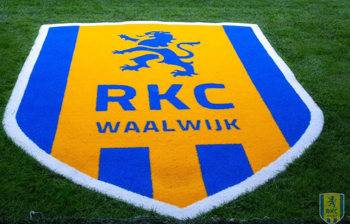 Het logo van RKC Waalwijk op het voetbalveld, een blauw en geel embleem met een staande leeuw en de naam van de club.