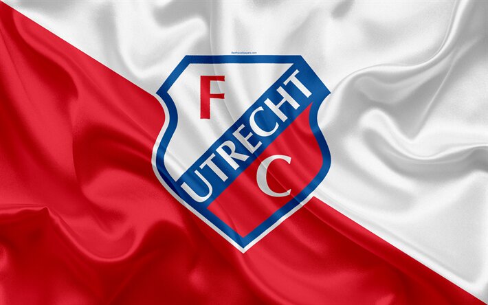 Het logo van FC Utrecht is prominent weergegeven op een zijdezachte rode en witte achtergrond, symboliserend de clubkleuren. Het herkenbare embleem toont een rood 'F' en 'C' tegen een witte achtergrond, met een blauwe omranding waarin 'Utrecht' staat geschreven.